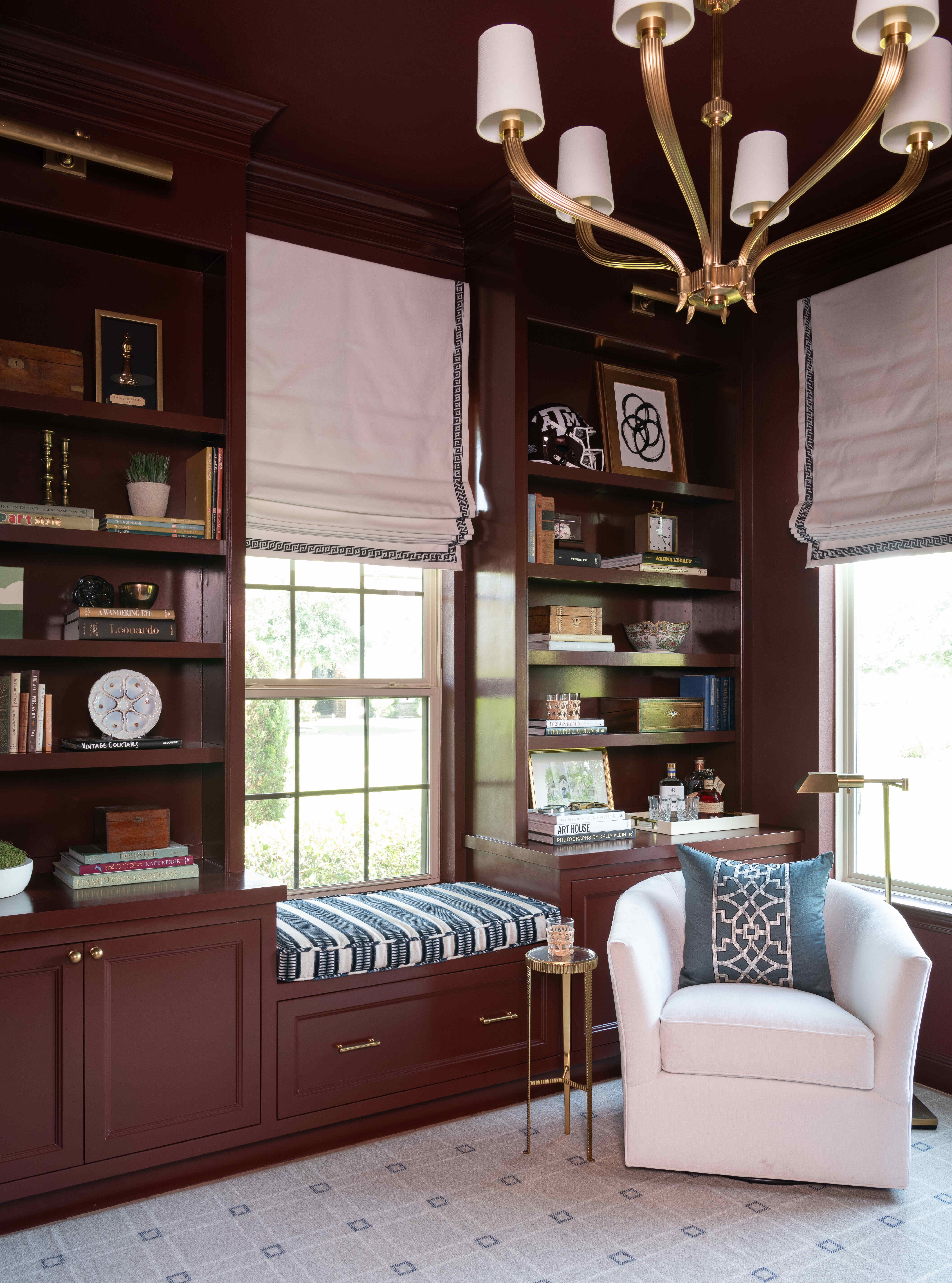 Custom library with maroon built-ins and brass fixtures Houston — Matt Baker Contracting